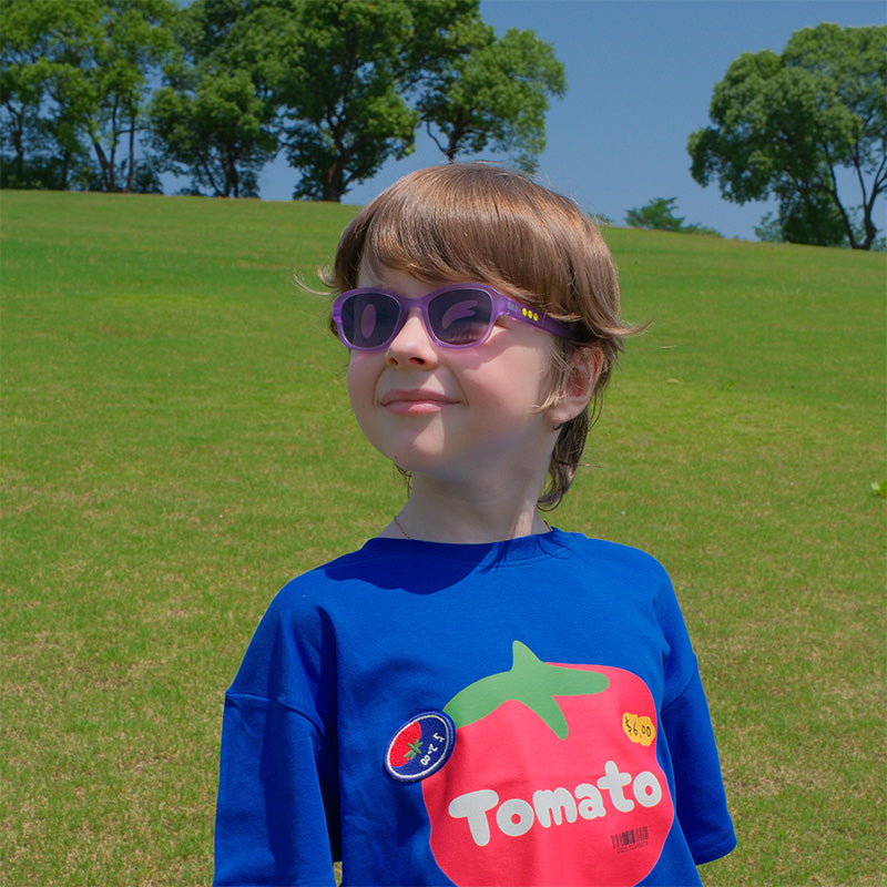 Happy child wearing SmileyWorld Coral Purple kids sunglasses playing outdoors.